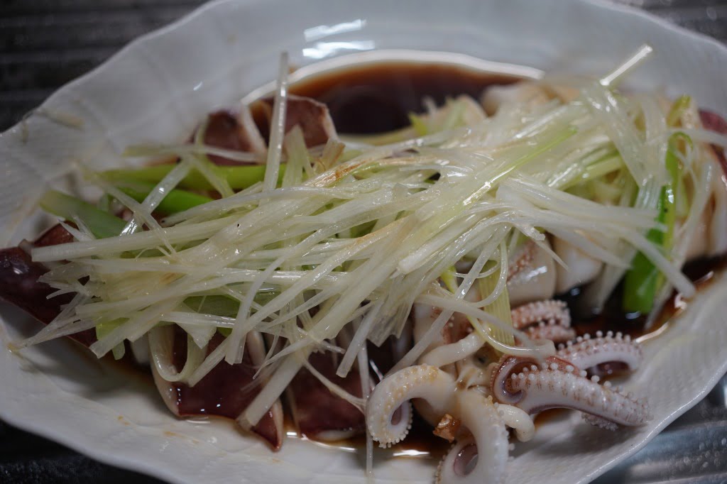 丸ごと茹でイカ醤油ソースがけ、熱々油をかけたネギ